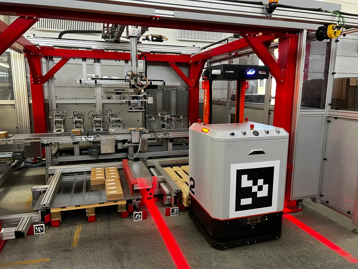 PIXEL PT inside the secured area of a packaging machine at Würth Industrie Service, beside a pallet of cartons on the infeed conveyor
